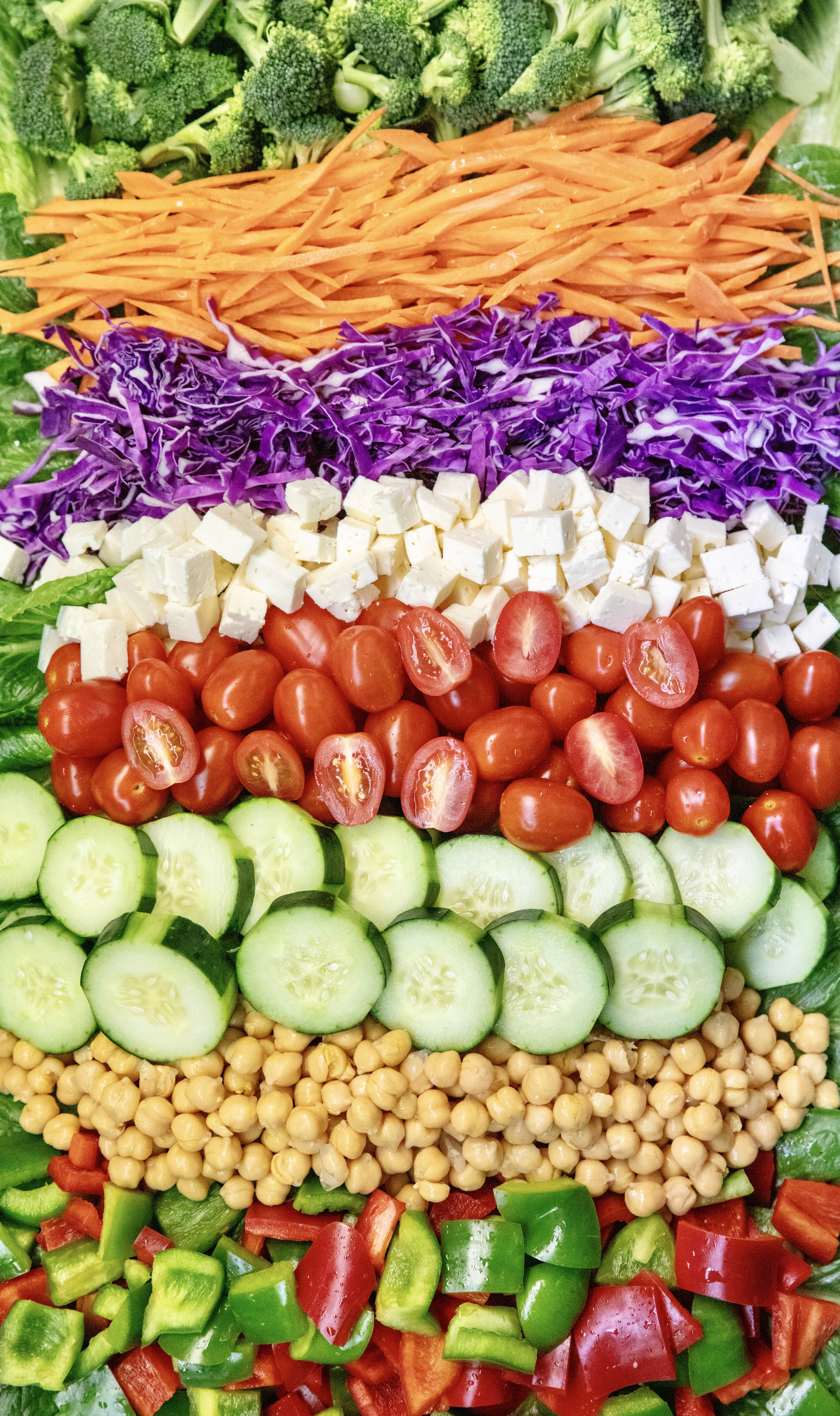 Salad bar toppings including broccoli, carrots, red cabbage, feta and tomatoes